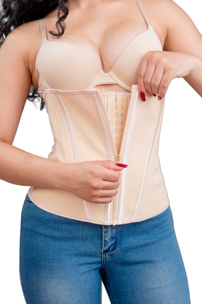 A woman in jeans fastens a beige waist trainer over a bra